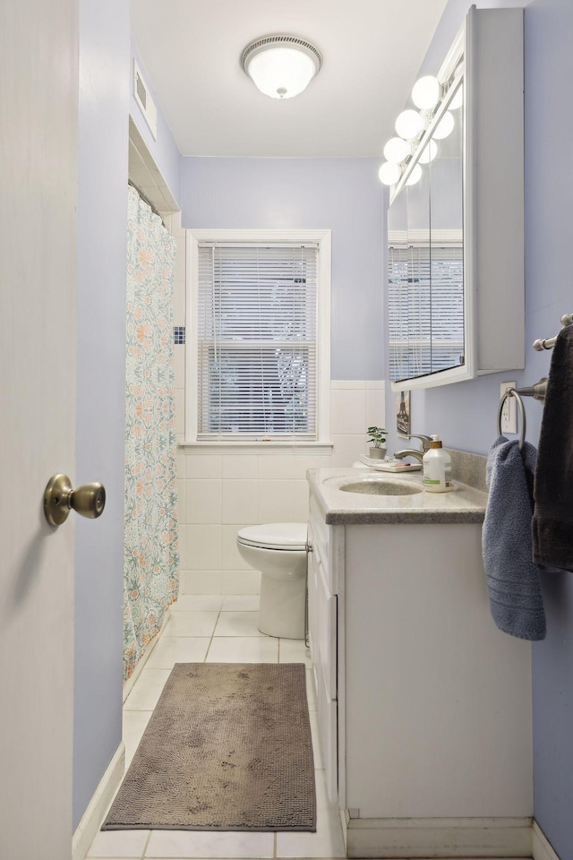 bathroom featuring tile patterned flooring, vanity, toilet, and tile walls