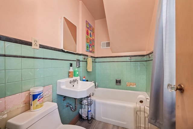 bathroom with wood-type flooring, sink, tile walls, and toilet