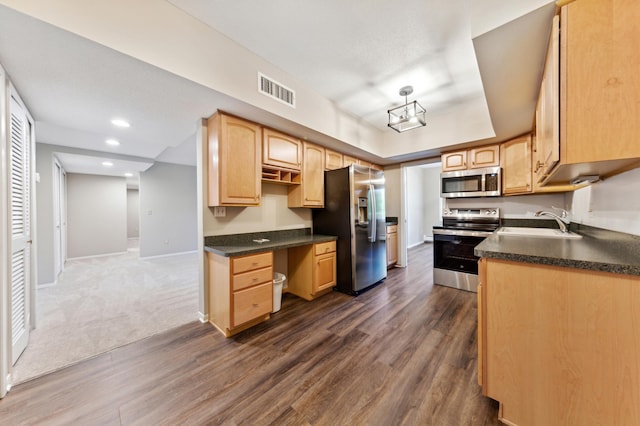 kitchen featuring sink, dark wood-type flooring, appliances with stainless steel finishes, built in desk, and light brown cabinets