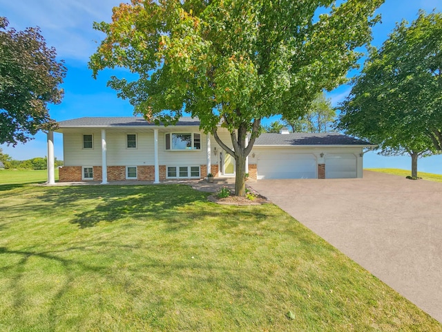 raised ranch featuring a garage and a front lawn