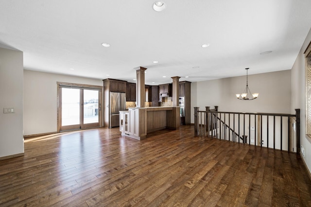 kitchen with dark wood-style flooring, freestanding refrigerator, light countertops, a chandelier, and pendant lighting