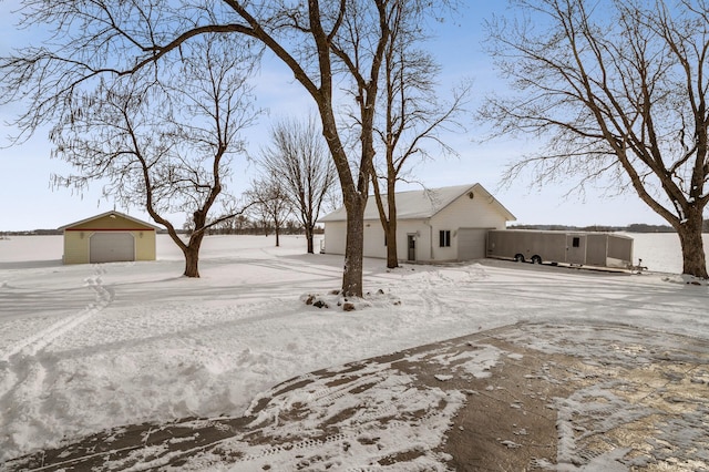 yard covered in snow featuring an outbuilding and a detached garage