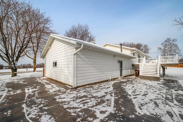 view of snow covered exterior with a deck and stairs