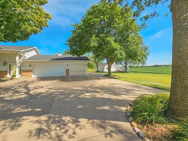 view of side of property with brick siding, a yard, driveway, and an attached garage