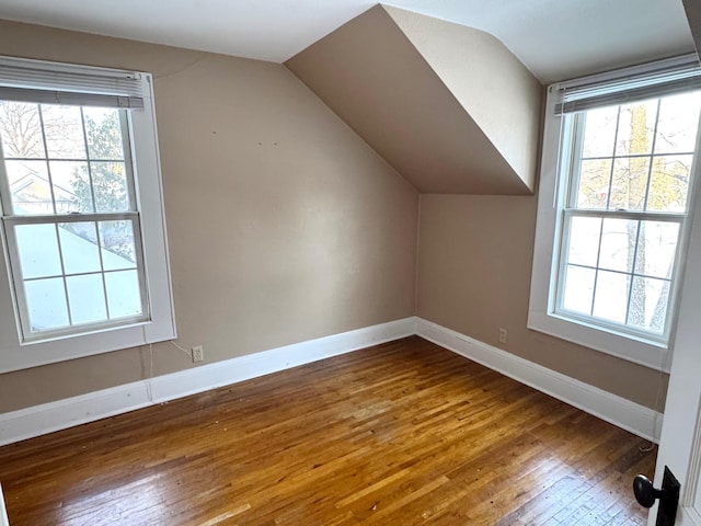 additional living space featuring vaulted ceiling, plenty of natural light, and dark hardwood / wood-style flooring