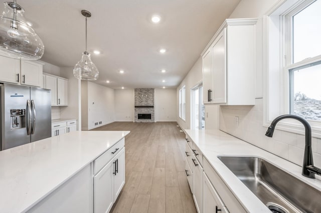 kitchen with a healthy amount of sunlight, sink, white cabinets, and stainless steel refrigerator with ice dispenser