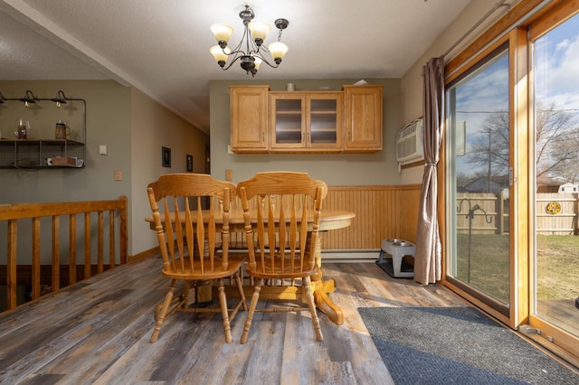 dining space with wood-type flooring, a wall mounted air conditioner, a textured ceiling, and an inviting chandelier