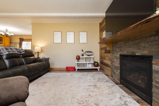 living room featuring an inviting chandelier, wood-type flooring, a fireplace, and a textured ceiling