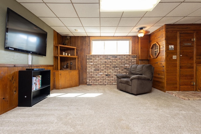 interior space with a drop ceiling, wooden walls, and carpet flooring