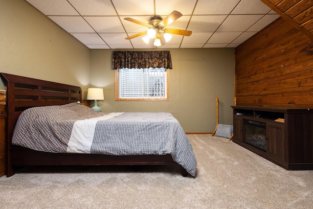 bedroom featuring light carpet, a drop ceiling, and wooden walls