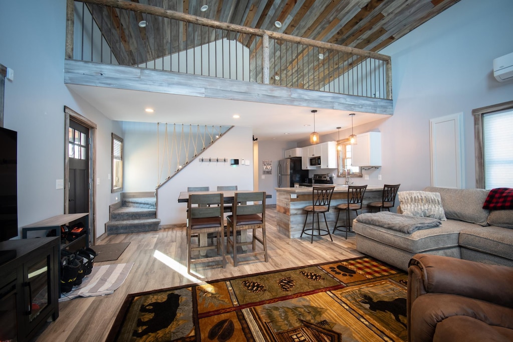 living room featuring a towering ceiling, light hardwood / wood-style flooring, and a wall unit AC