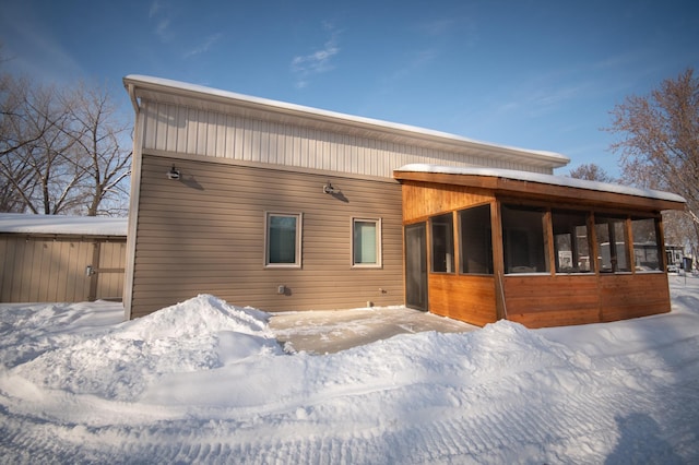 snow covered house featuring a sunroom