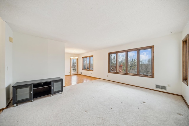 unfurnished living room featuring a notable chandelier and light colored carpet