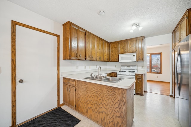 kitchen with sink, a textured ceiling, white appliances, and kitchen peninsula