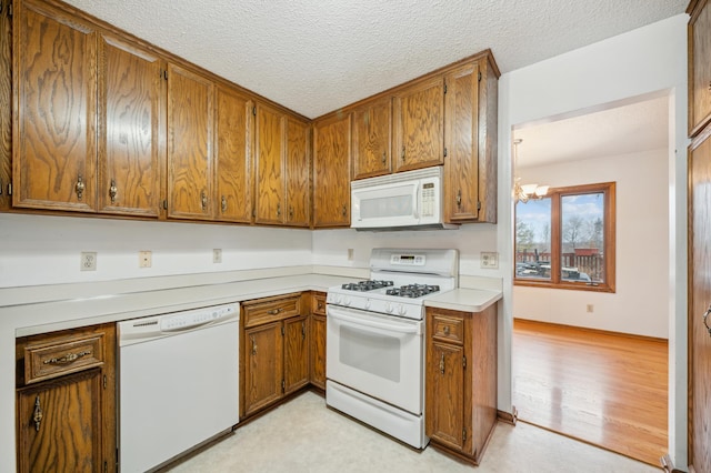 kitchen with white appliances, light hardwood / wood-style floors, a textured ceiling, and a notable chandelier