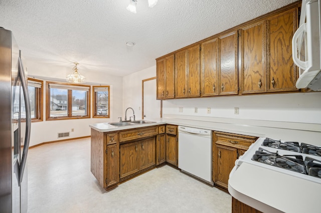 kitchen with white appliances, kitchen peninsula, sink, and a textured ceiling