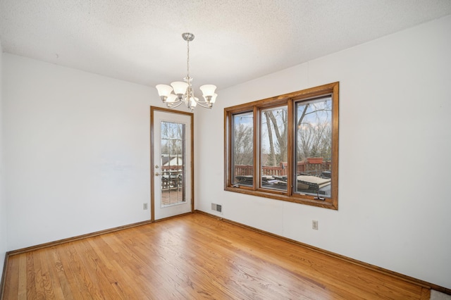 unfurnished room with wood-type flooring, a textured ceiling, and an inviting chandelier