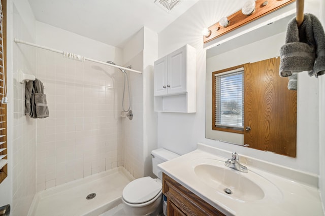 bathroom featuring vanity, toilet, and a tile shower