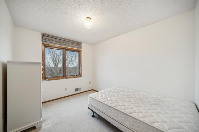 bedroom featuring light carpet and a textured ceiling