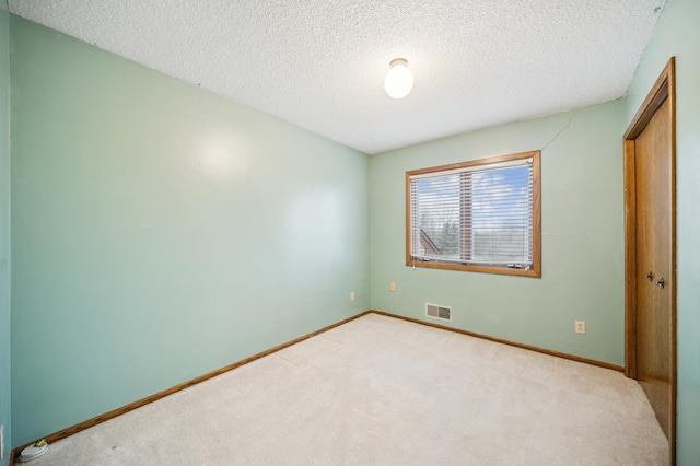 unfurnished bedroom with light carpet, a textured ceiling, and a closet