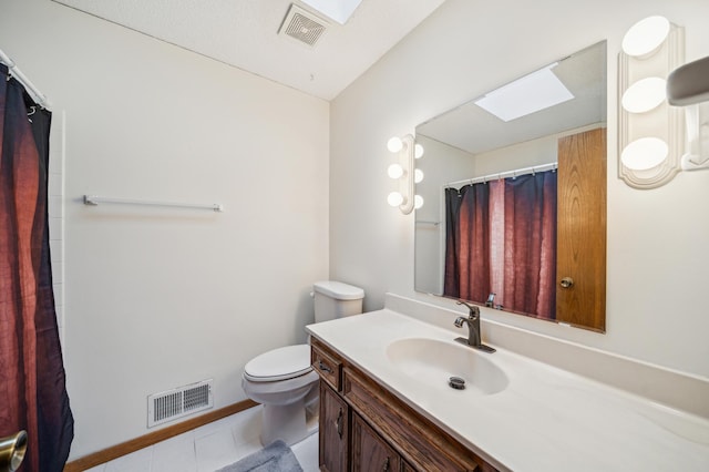 bathroom featuring tile patterned floors, vanity, toilet, and a skylight