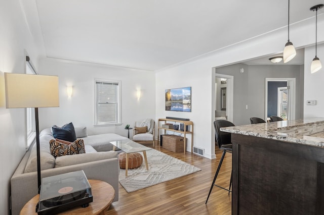 living area featuring visible vents and wood finished floors