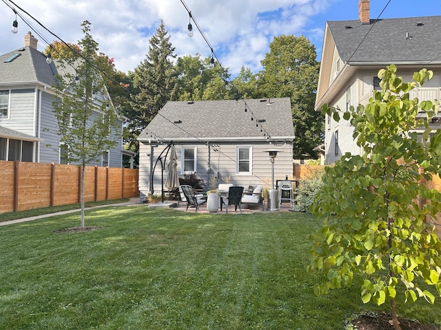 rear view of property with a patio, a shingled roof, a lawn, and a fenced backyard