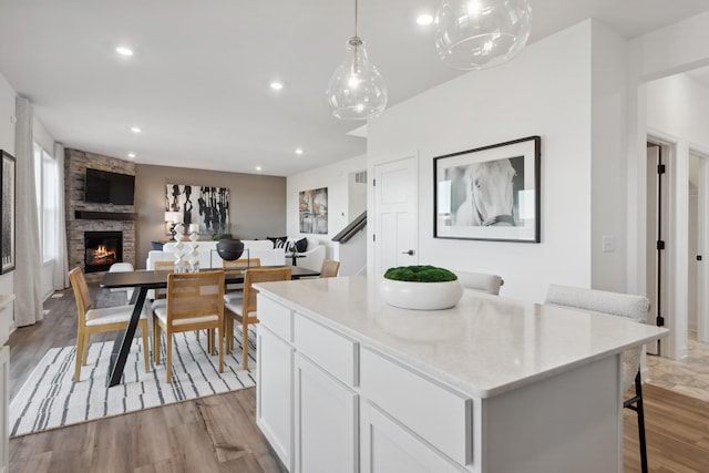 kitchen featuring pendant lighting, a kitchen island, light hardwood / wood-style floors, white cabinets, and a kitchen bar