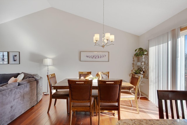 dining room with lofted ceiling, hardwood / wood-style floors, and a chandelier