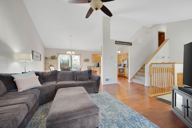 living room featuring ceiling fan with notable chandelier, hardwood / wood-style floors, and high vaulted ceiling