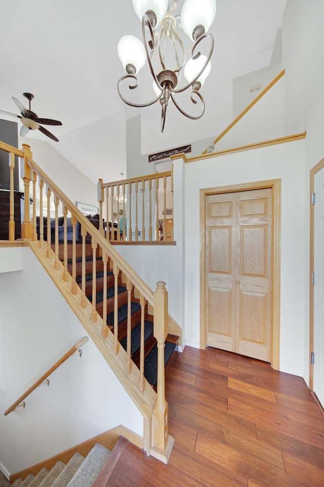 stairway featuring ceiling fan with notable chandelier and hardwood / wood-style floors