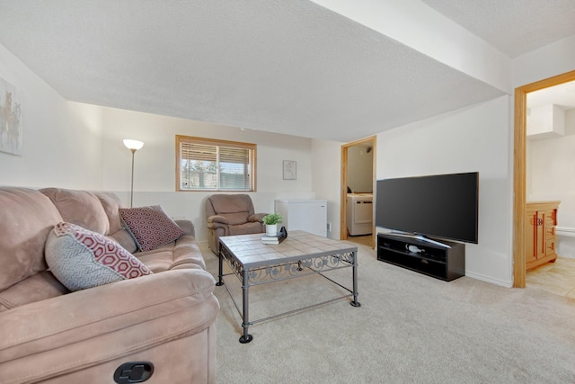 living room with washer / clothes dryer, light carpet, and a textured ceiling