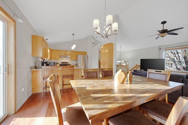 dining room with high vaulted ceiling, ceiling fan with notable chandelier, and light wood-type flooring