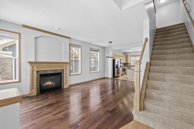 unfurnished living room featuring wood-type flooring, a premium fireplace, and a textured ceiling