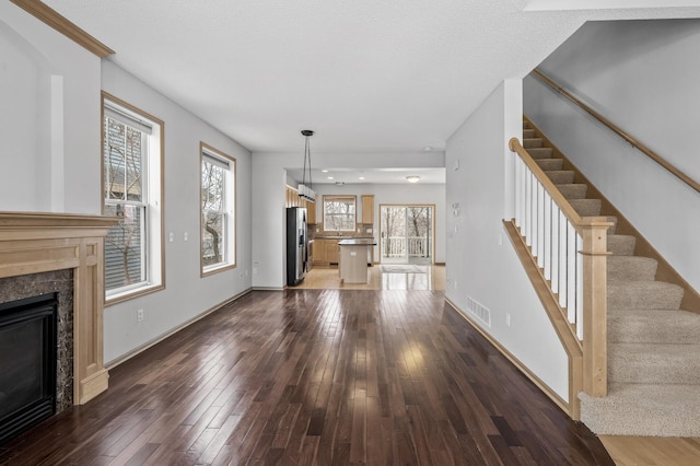 unfurnished living room with dark wood-type flooring, a fireplace, a textured ceiling, and a wealth of natural light