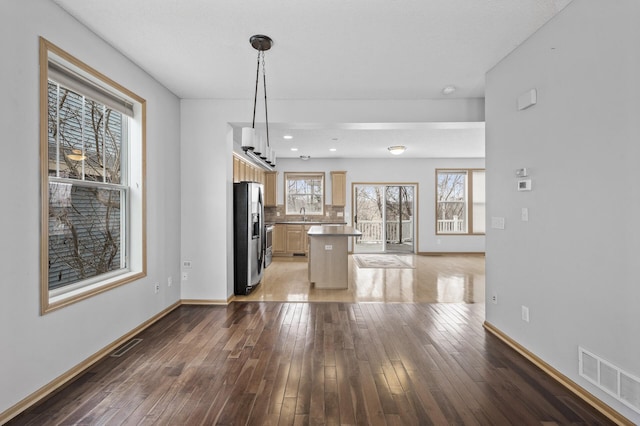 kitchen featuring stainless steel refrigerator with ice dispenser, wood-type flooring, decorative light fixtures, and a center island