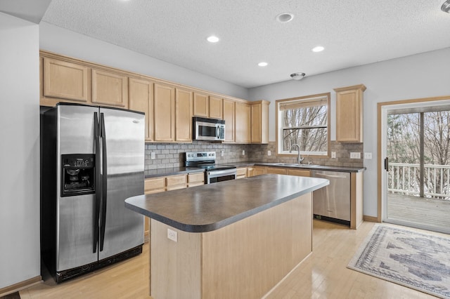 kitchen with stainless steel appliances, a kitchen island, sink, and light hardwood / wood-style floors