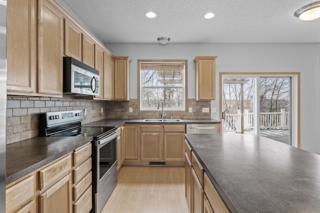 kitchen featuring sink, stainless steel appliances, tasteful backsplash, a textured ceiling, and light wood-type flooring