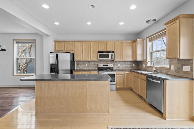 kitchen featuring appliances with stainless steel finishes, a center island, sink, and light brown cabinets