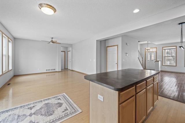 kitchen with a kitchen island, ceiling fan with notable chandelier, light hardwood / wood-style floors, and decorative light fixtures