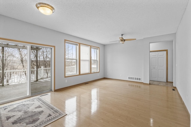 empty room with ceiling fan, a textured ceiling, and light wood-type flooring