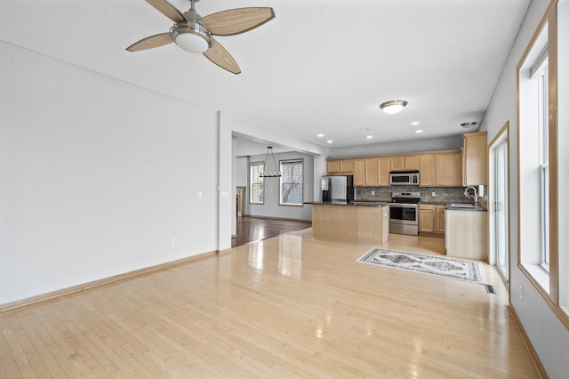 kitchen featuring tasteful backsplash, sink, hanging light fixtures, light hardwood / wood-style floors, and stainless steel appliances