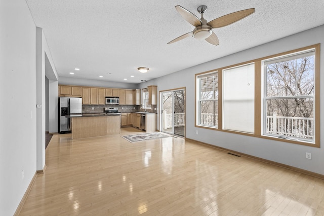 kitchen with backsplash, stainless steel appliances, light hardwood / wood-style floors, and a textured ceiling