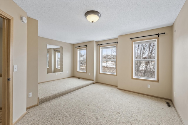 carpeted spare room featuring a textured ceiling