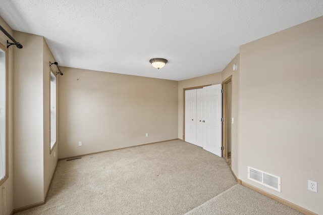 unfurnished bedroom featuring carpet, a textured ceiling, and a closet