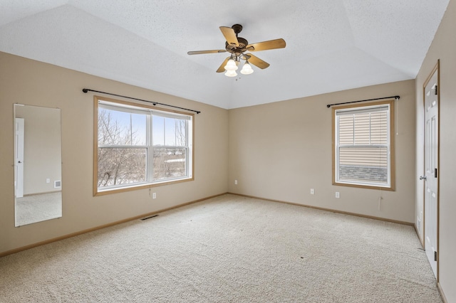 carpeted spare room with vaulted ceiling, ceiling fan, and a textured ceiling