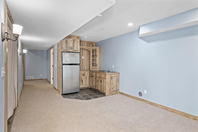 kitchen featuring dark colored carpet, sink, light brown cabinetry, and stainless steel refrigerator