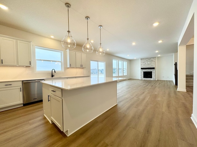 kitchen featuring white cabinetry, a center island, light hardwood / wood-style floors, decorative light fixtures, and stainless steel dishwasher