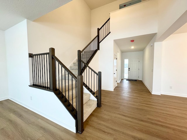 staircase featuring hardwood / wood-style flooring and a towering ceiling