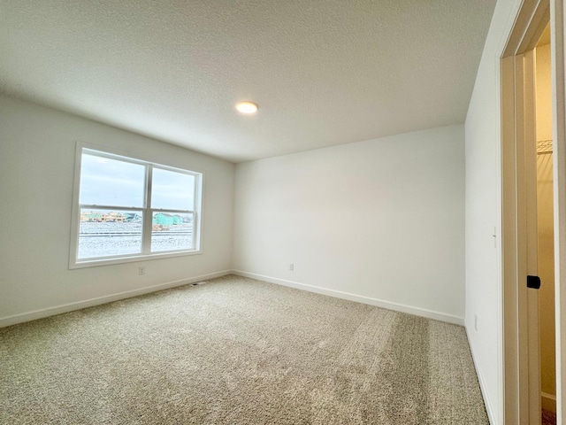 carpeted empty room featuring a textured ceiling